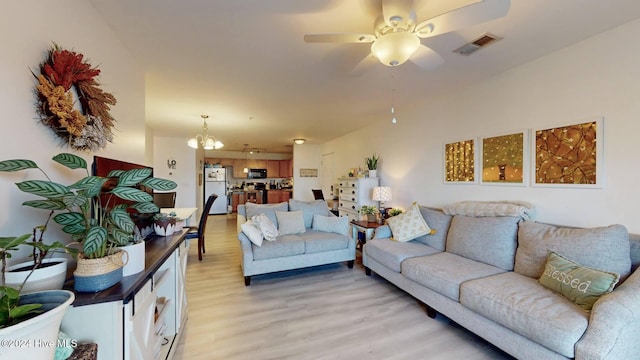 living room with ceiling fan with notable chandelier and light hardwood / wood-style floors