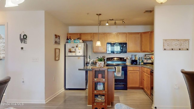 kitchen featuring decorative light fixtures, light hardwood / wood-style flooring, and black appliances