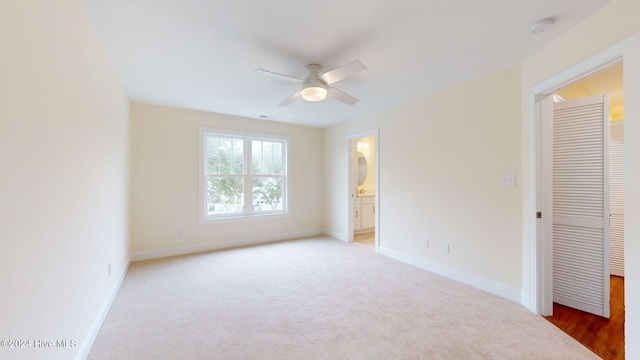 unfurnished bedroom featuring ensuite bath, ceiling fan, a closet, and carpet floors