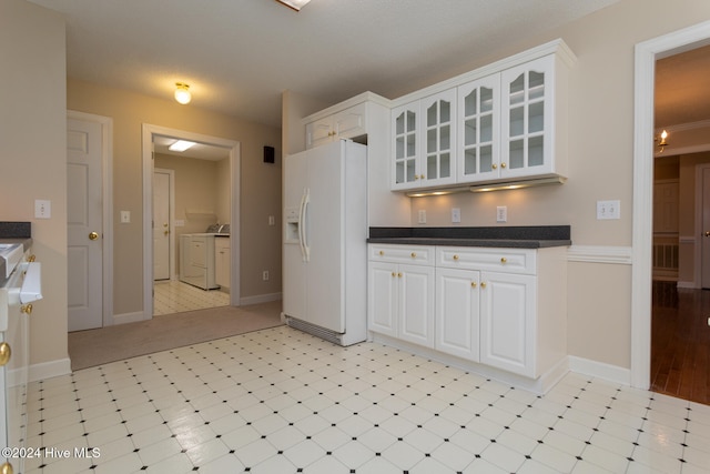 kitchen with white refrigerator with ice dispenser, independent washer and dryer, a textured ceiling, light tile patterned flooring, and white cabinetry