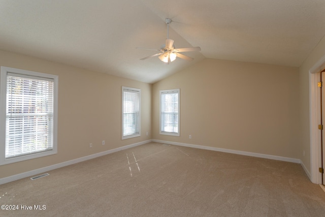 carpeted spare room featuring a wealth of natural light, ceiling fan, and vaulted ceiling