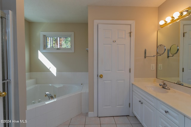 bathroom with tile patterned flooring, vanity, a relaxing tiled tub, and a textured ceiling