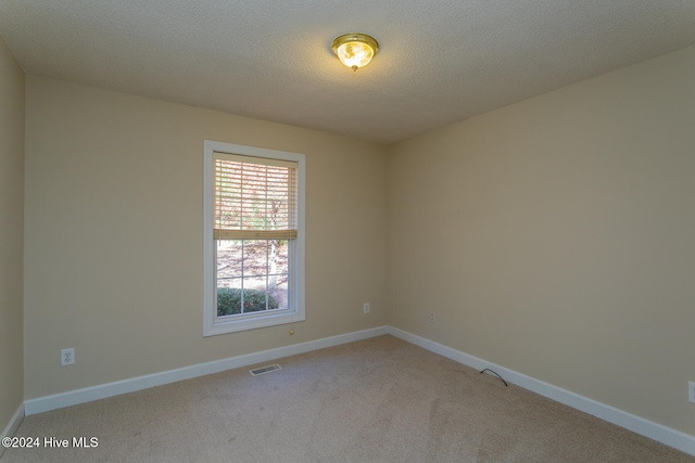 empty room with a textured ceiling and light colored carpet