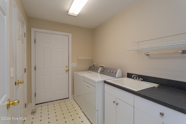 washroom featuring washing machine and clothes dryer, sink, cabinets, and a textured ceiling