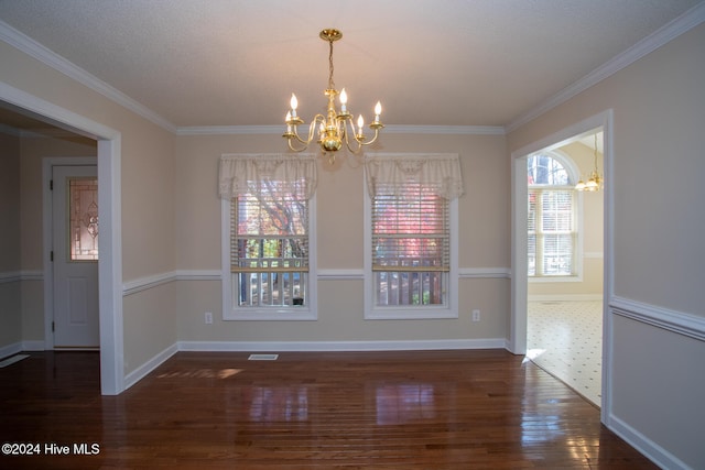 unfurnished dining area with a notable chandelier, dark hardwood / wood-style floors, crown molding, and a wealth of natural light