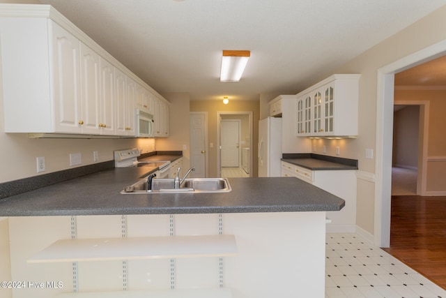 kitchen with kitchen peninsula, white appliances, sink, light hardwood / wood-style flooring, and white cabinetry