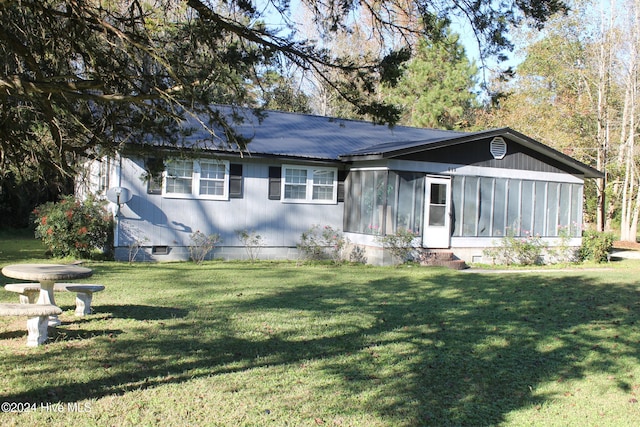 back of property featuring a lawn and a sunroom