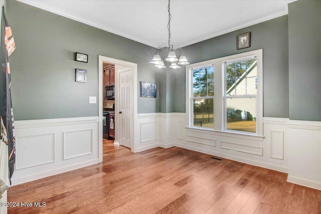 unfurnished dining area with light hardwood / wood-style floors, crown molding, and a notable chandelier