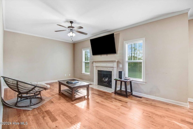 living room with a wealth of natural light, ceiling fan, a premium fireplace, and light wood-type flooring