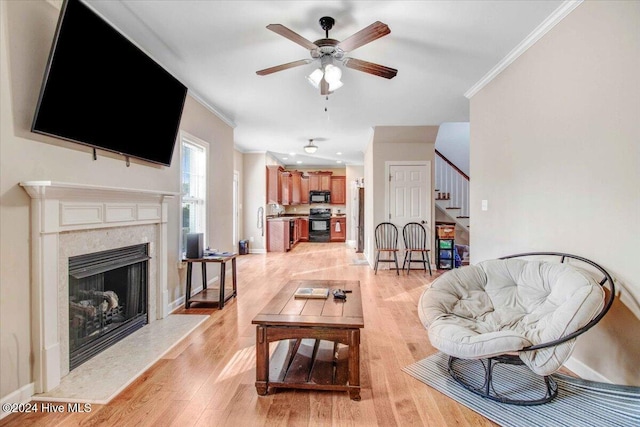 living room featuring sink, ceiling fan, ornamental molding, a fireplace, and light hardwood / wood-style floors