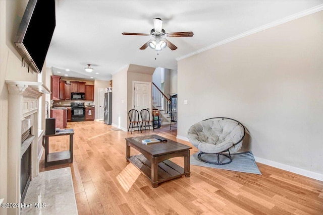 living room with ceiling fan, crown molding, and light hardwood / wood-style flooring