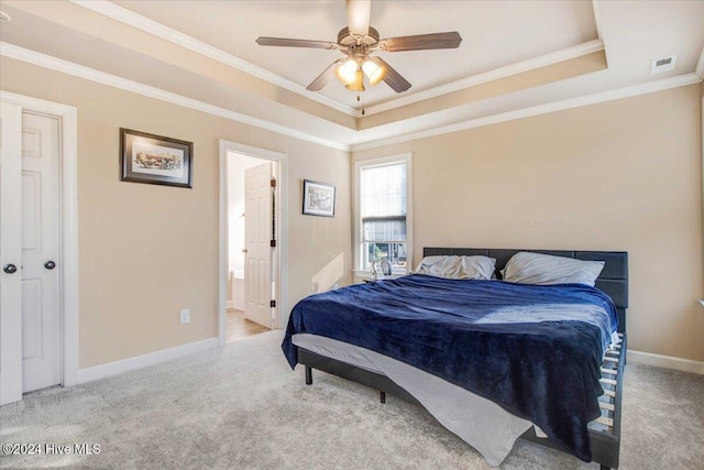 carpeted bedroom featuring ceiling fan, a raised ceiling, ornamental molding, and ensuite bath