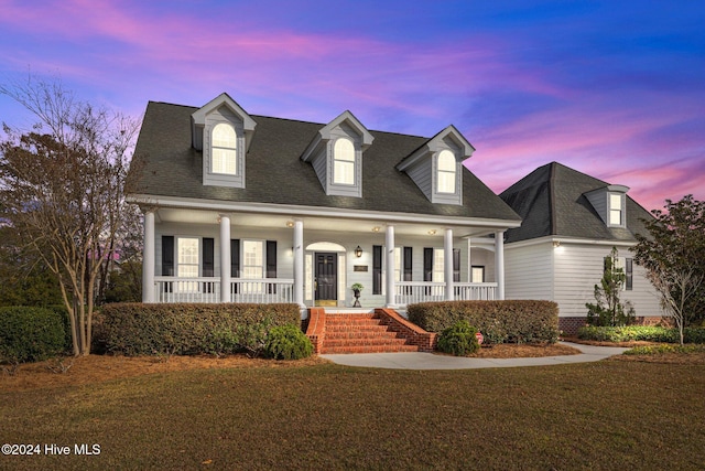 cape cod-style house with a porch and a yard