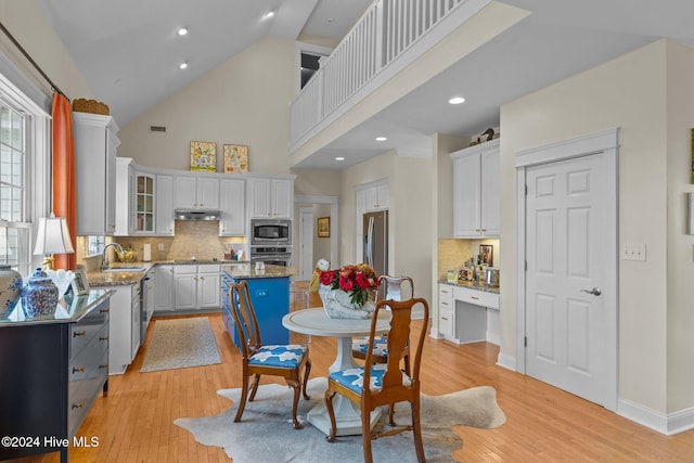 kitchen featuring white cabinets, stainless steel appliances, a kitchen island, and light hardwood / wood-style flooring