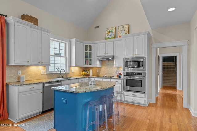1502 Marsh Pointe, Morehead City, NC 28557 - kitchen featuring appliances with stainless steel finishes, under cabinet range hood, light wood-style flooring, white cabinetry, and high vaulted ceiling