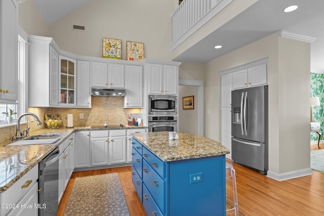 kitchen featuring a center island, light wood-type flooring, white cabinetry, and appliances with stainless steel finishes