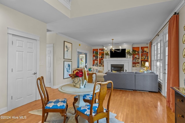 dining room featuring ornamental molding, light wood-type flooring, a brick fireplace, and a notable chandelier