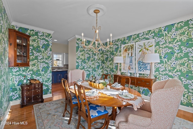 dining room with sink, light hardwood / wood-style flooring, a chandelier, and ornamental molding