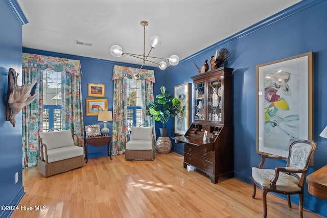 sitting room featuring light hardwood / wood-style flooring, crown molding, and a notable chandelier