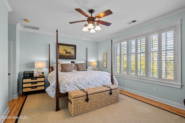 bedroom with ceiling fan, light wood-type flooring, ornamental molding, and multiple windows