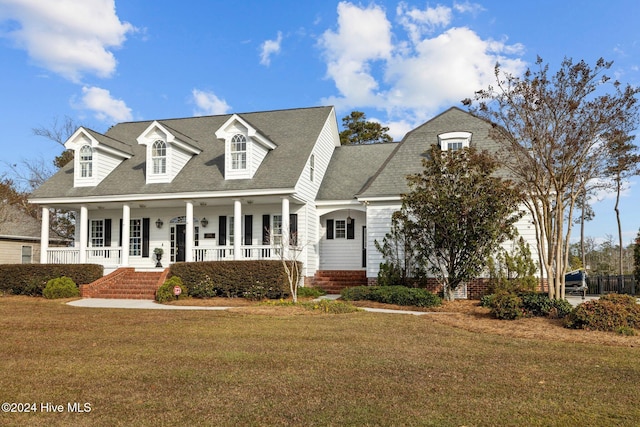 cape cod house featuring covered porch and a front lawn