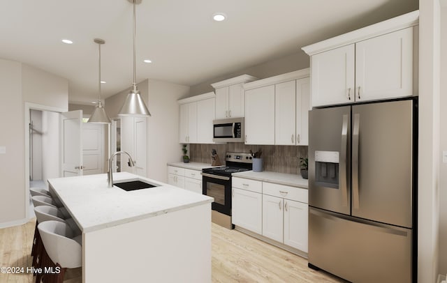 kitchen featuring stainless steel appliances, sink, pendant lighting, white cabinetry, and an island with sink