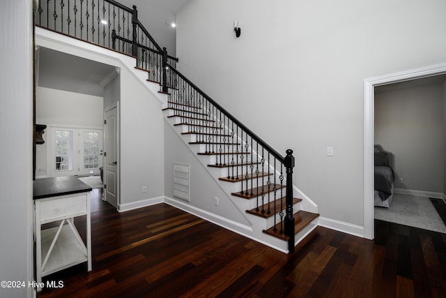 staircase with a high ceiling, hardwood / wood-style flooring, and french doors