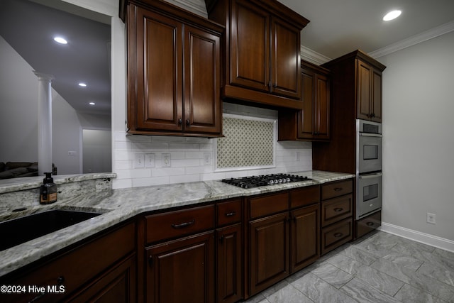 kitchen with backsplash, ornamental molding, appliances with stainless steel finishes, dark brown cabinetry, and decorative columns