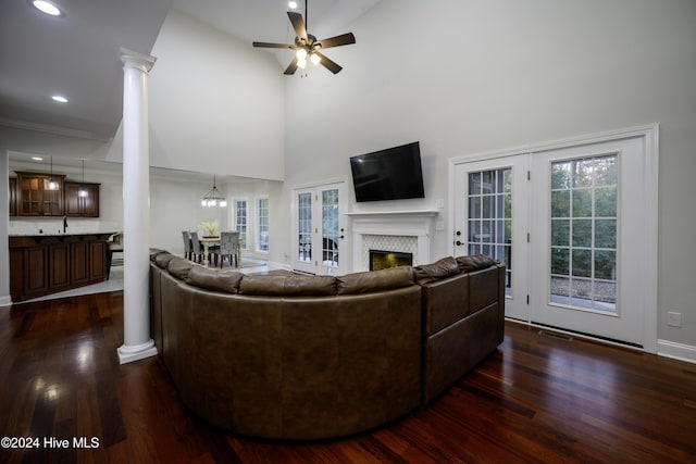 living room with a tile fireplace, sink, dark hardwood / wood-style flooring, a towering ceiling, and ceiling fan with notable chandelier