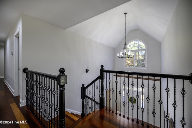 stairs featuring hardwood / wood-style floors, vaulted ceiling, and an inviting chandelier