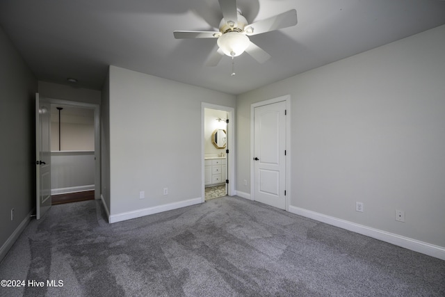 unfurnished bedroom with dark colored carpet, ensuite bath, and ceiling fan