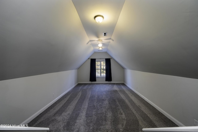 additional living space with dark carpet and lofted ceiling