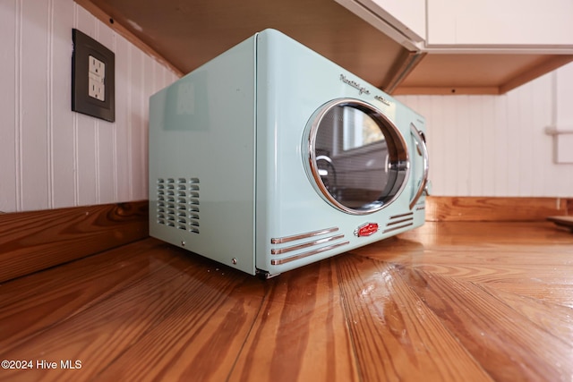 washroom with hardwood / wood-style floors, wooden walls, and washer / clothes dryer