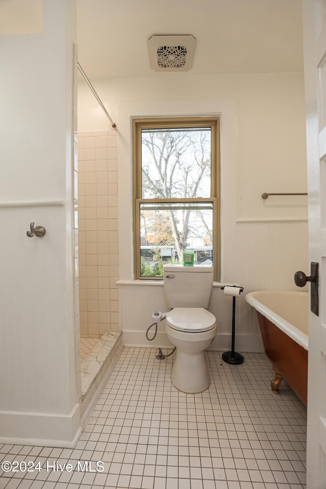 bathroom with tile patterned flooring, toilet, and tiled shower