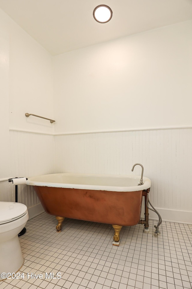 bathroom with a bathing tub, tile patterned flooring, and toilet