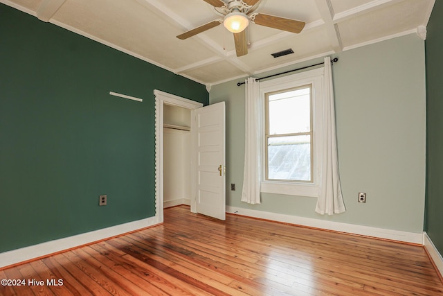 unfurnished bedroom featuring ceiling fan, wood-type flooring, coffered ceiling, and ornamental molding