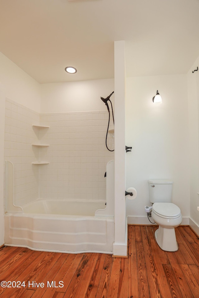 bathroom with tiled shower / bath combo, toilet, and wood-type flooring