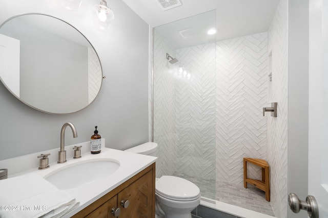 bathroom featuring vanity, toilet, and a tile shower