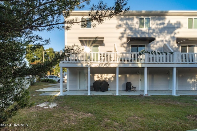 rear view of house featuring a lawn, a wooden deck, and a patio