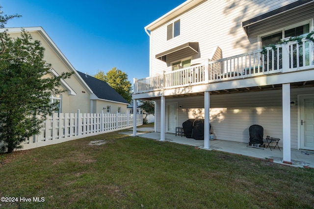 back of property featuring a balcony, a patio area, and a lawn