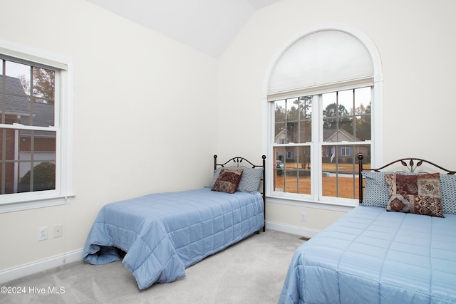 bedroom featuring multiple windows, vaulted ceiling, and carpet flooring