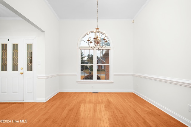 unfurnished dining area with a chandelier, ornamental molding, wood finished floors, and baseboards