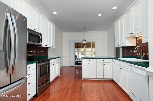 kitchen featuring stainless steel appliances, dark countertops, white cabinetry, and a sink