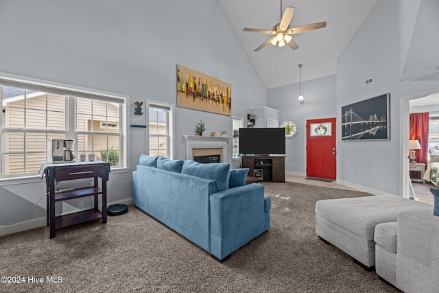 carpeted living room featuring a tile fireplace, high vaulted ceiling, and ceiling fan