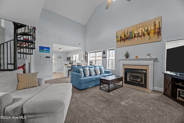 carpeted living room featuring a tile fireplace, high vaulted ceiling, and ceiling fan