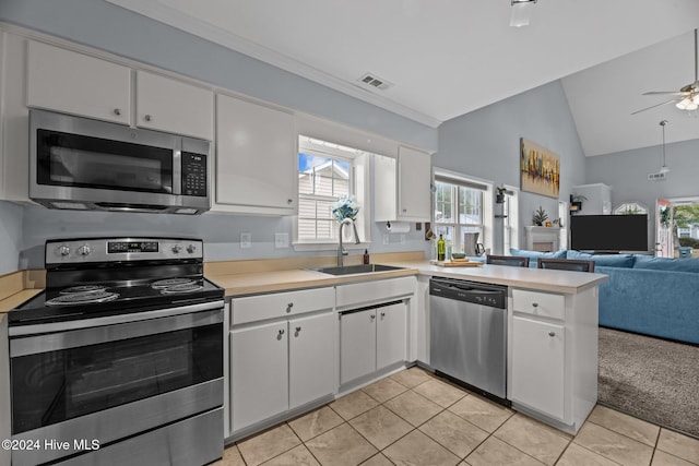 kitchen featuring sink, light tile patterned flooring, vaulted ceiling, white cabinets, and appliances with stainless steel finishes