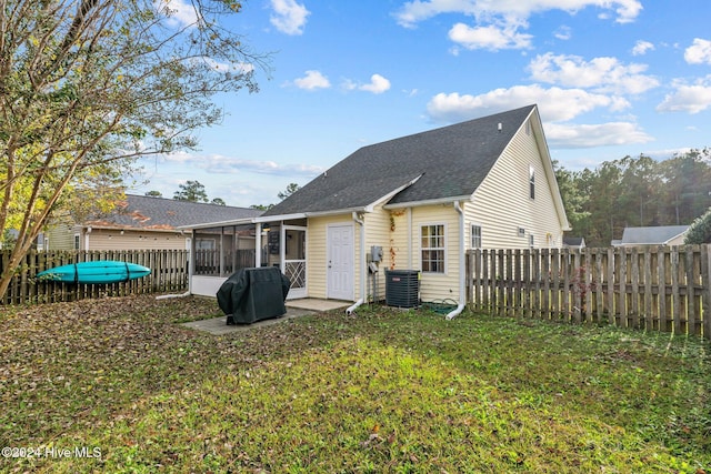 rear view of property featuring central AC, a sunroom, and a yard