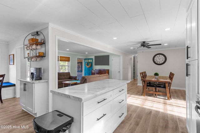 kitchen with light hardwood / wood-style flooring, light stone countertops, a kitchen island, and white cabinets