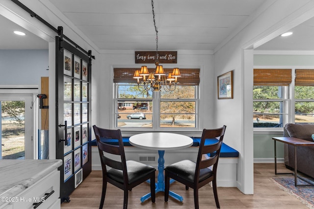 dining room featuring wood-type flooring, a barn door, and a chandelier