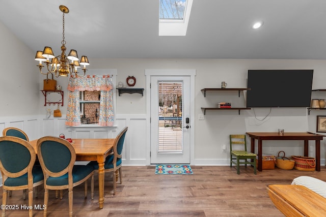 dining room featuring an inviting chandelier, a skylight, and light hardwood / wood-style flooring